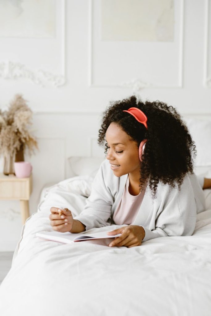 Outsourcing reduces overwhelm by letting you do the things you love, when you want to do them, from where you want to be. Image of women on a bed listening to music. 